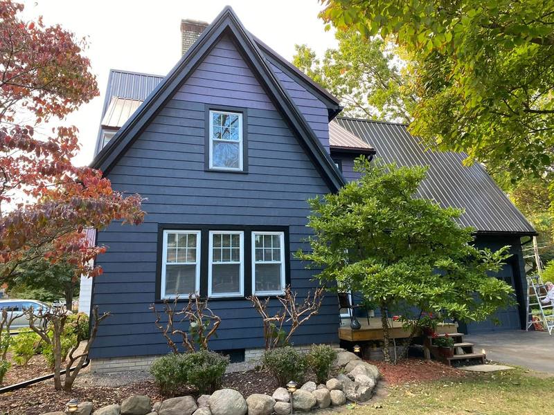 After: the same house with its siding painted a dark blue-purple and crisp white window trim, painted by Whiteout Painting