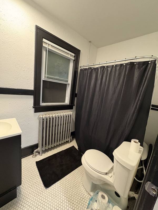 Bathroom with white walls, black window trim and hex tile floor
